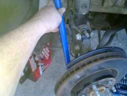 Using a crow bar to remove the existing brake rotor